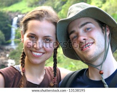 A close portrait of a happy hiking couple with greenery and waterfall in background. Hawaii, USA.