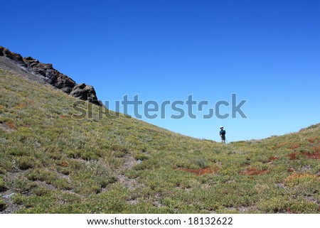 A lone hiker in a steep mountain saddle in the Sierra Nevada mountains.  California, U.S.A