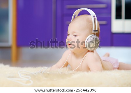 6 month baby photo shoot in white headphones with crystals on a beige fur on the floor