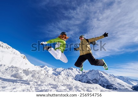 woman and a man in a jump in the mountains of Austria against the blue sky and snow-capped mountains