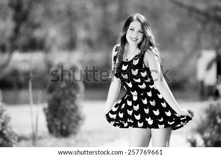 Beautiful young girl with long hair on nature in black short dress with kittens, black and white