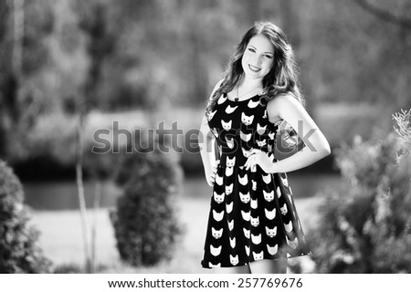 Beautiful young girl with long hair on nature in black short dress with kittens, black and white