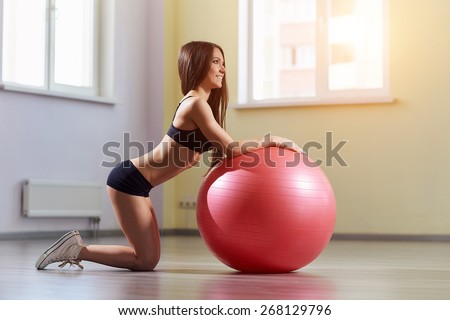 Fitness woman in gym resting on pilates ball. Young woman doing exercise on fitness ball. Young girl on the pink fitness ball in gym. Girl with fitness ball. Beautiful girl doing exercises with ball.