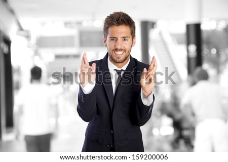 young businessman finger crossing in a company