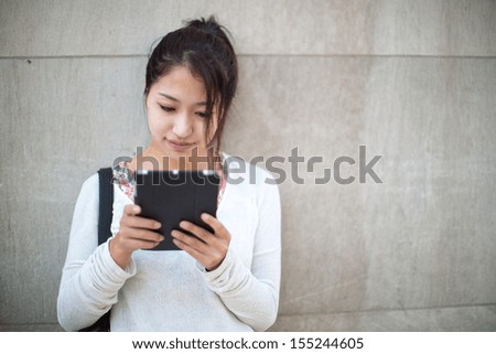Asian woman using tablet pc computer outdoor on a city street