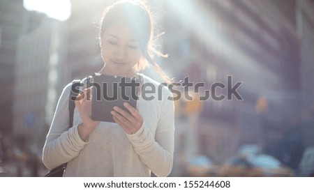 Asian woman using tablet pc computer outdoor on a city street Asian woman using tablet pc computer outdoor on a city street