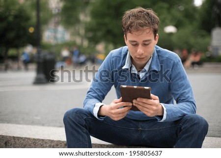 Young caucasian man in New York City using tablet pc computer in a park