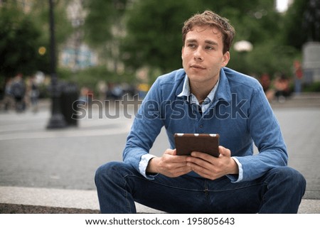 Young caucasian man in New York City using tablet pc computer in a park