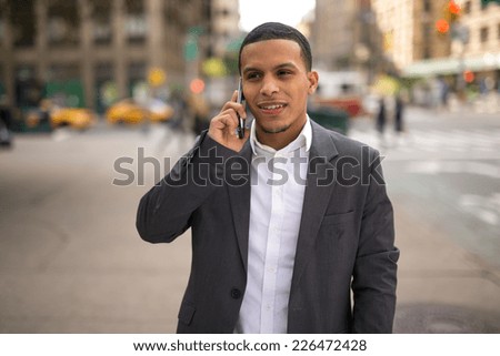 Young African American black Latino man talking on cellphone on city street