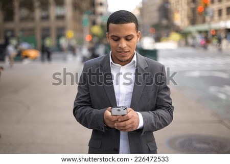 Young African American black Latino man texting cellphone on city street