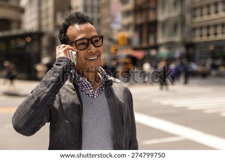 Young Black African Asian mixed man in city talking on cell phone