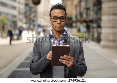 Young black African Asian man in city using tablet pc computer