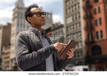 Young black African Asian man in city using tablet pc computer