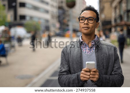 Young black African Asian man in city texting cell phone email