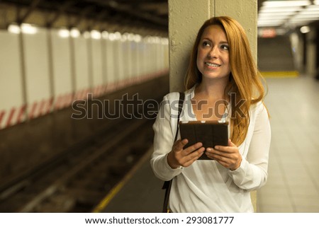 Young Caucasian woman using tablet pc computer at subway platform in New York City