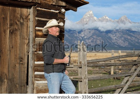 Cowboy drinking morning coffee near farm ranch barn