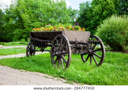 Old wooden cart full of flowers in garden