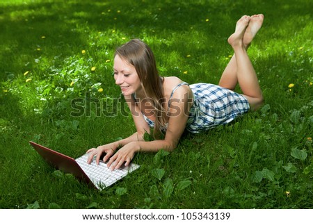 Attractive woman lying on grass with laptop in the park
