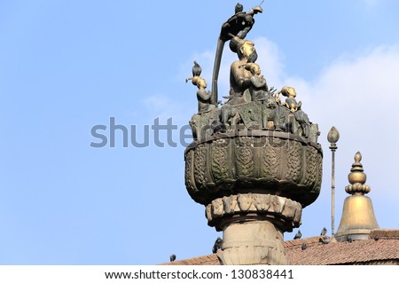 Brass statue of King Pratap Malla surrounded by his two wives and his five sons atop the square stone pillar Pratap Dhvaja. Durbar Square-Kathmandu-Nepal.