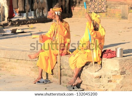 KATHMANDU, NEPAL - OCTOBER 4, : Two saffron dressed sadhus sit on a brick layer to be seen by their faithful on October 4, 2012 in the Durbar Square-Kathmandu-Nepal.