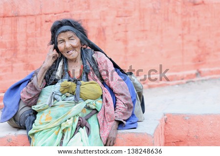 KATHMANDU, NEPAL - OCTOBER 4: Old woman sits down to take a rest and starts preparing for begging at the people passing by and trying to benefit from the tourists on October 4, 2012 in Kathmandu-Nepal