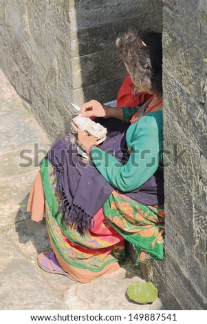 DEOPATAN, KATHMANDU, NEPAL - OCTOBER 5: Woman counts money after a morning selling food to faithfuls-offering to priests and sadhus on October 5, 2012 in Pashupatinath temple-Deopatan-Kathmandu-Nepal.