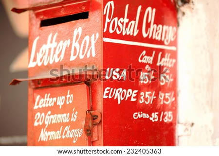 Red painted mailbox with white lettering showing the postal rates on the main street of Pokhara-Kaski district-Gandaki zone-Nepal.