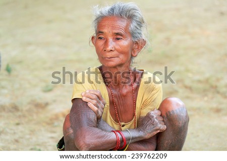 PATIHANI, NEPAL - OCTOBER 13: Old woman of the tharu people exhibits her ethnical tattoos to the tourists while sitting on the floor on October 13, 2012 in Patihani-Chitwan distr.-Narayani Zone-Nepal.
