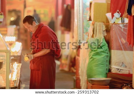 DREPUNG, TIBET, CHINA - OCTOBER 19: Tibetan buddhist monk lights candles in the Sutra Hall of the Coqen Hall on October 19, 2012 in Drepung-Rice Heap monastery. Lhasa pref.-Tibet A.R.-China.