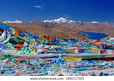 Prayer flags on Kamba La-pass over the 638 km2-130 km.E\'W-70 km.N\'S wide-4441 ms.high-turquoise colored Yamdrok Tso-Upper Pasture lake and 7206 ms.high mt.Nojin Kangsang. Lhoka or Shannan pref.-Tibet.