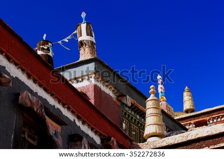Gilded brass and fabric dhvajas-victory banners on rooftop-fabric canopy-prayer flags. Shrine on grounds of the 1073 AD-Khon Konchog Gyalpo built North Seat Sakya-Grey Soil monastery. Sakya-Tibet.