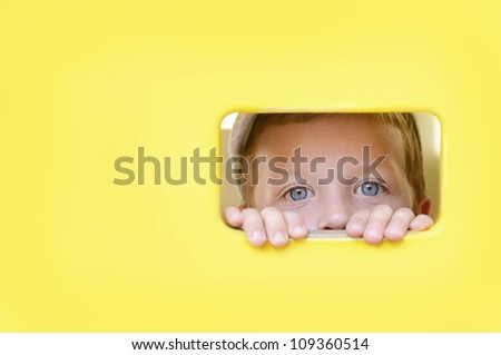 Cute boy peeping through the hole in wooden wall