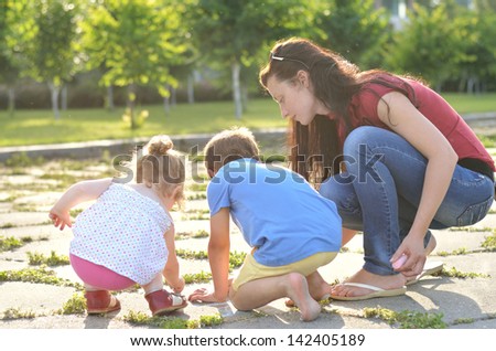 Mother and shildren drawing with chalk outdors