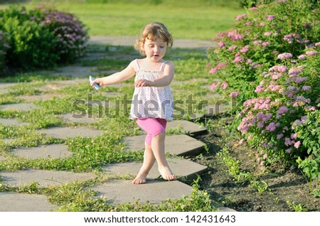 Funny active girl walking with a chalk on a brick path in the park