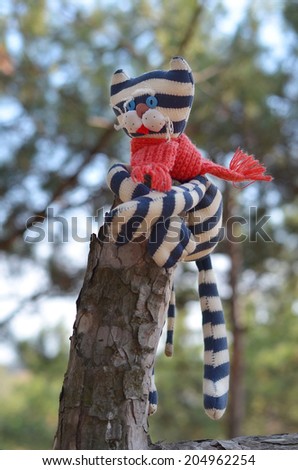 Striped funny cat hanging on top of pine stem