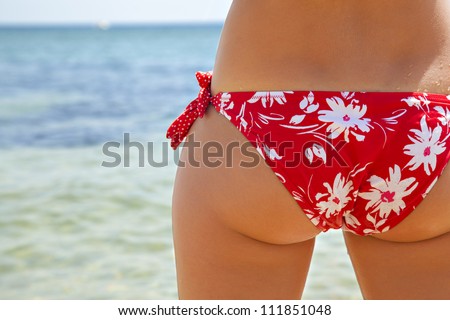 girl in a red bikini at sea, girl tanning on the beach in a red bathing suit