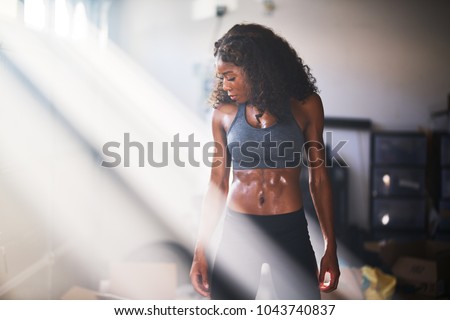 muscular african american woman sweating from work out in home gym