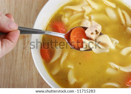Hand using spoon to eat chicken Noodle soup