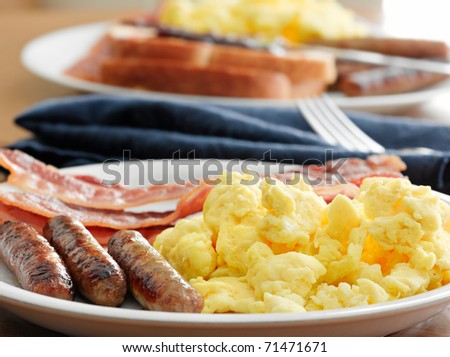 breakfast meal with sausage and scrambled eggs with bacon.