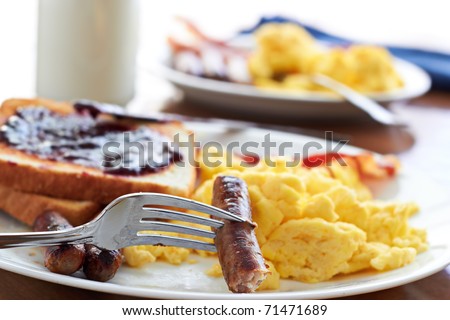 sausage links being pick up by a fork at a big breakfast.