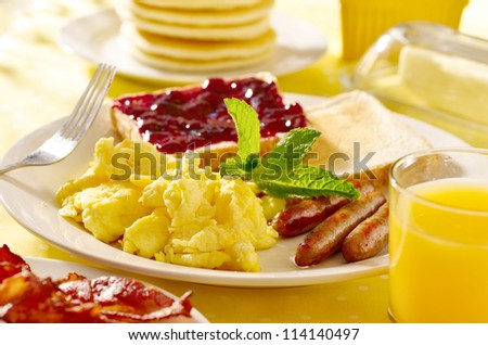 breakfast with scrambled eggs, sausage links and toast.