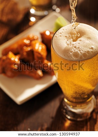 pouring beer with chicken wings in background pouring beer with chicken wings in background