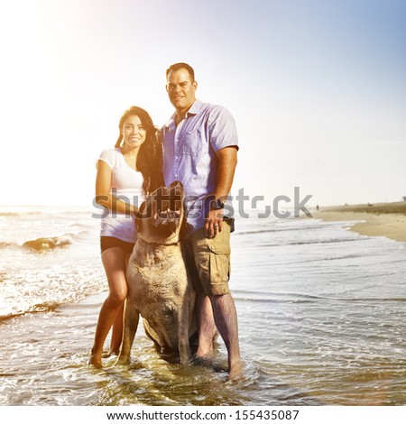 couple together with pet dog posing on the beach.