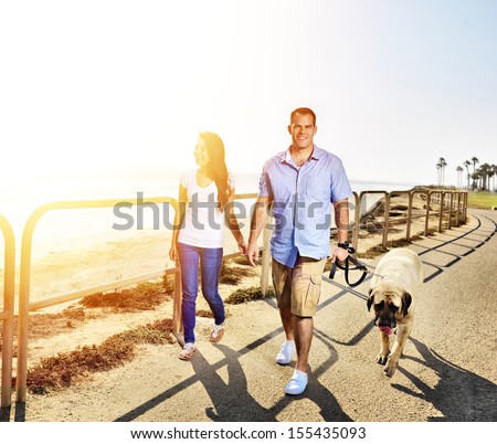 couple walking pet dog by the ocean