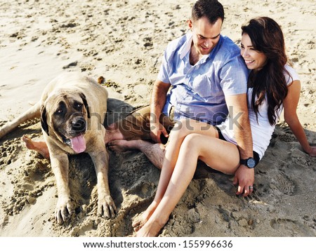couple relaxing with pet dog on the beach.