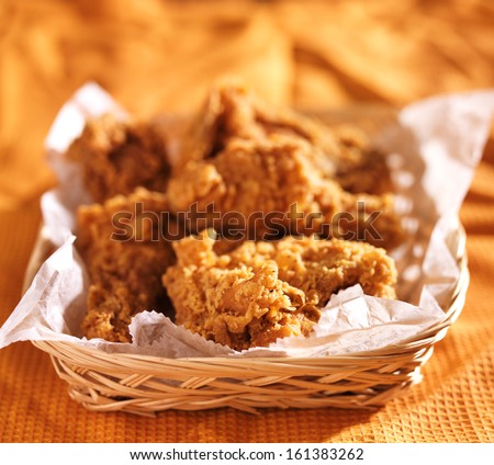 crispy fried chicken in basket on orange table cloth