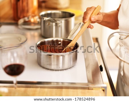 stirring a small pot of spaghetti sauce on the stove