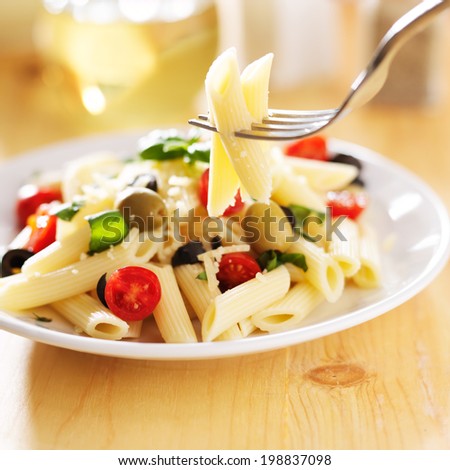 eating penne pasta salad with fork
