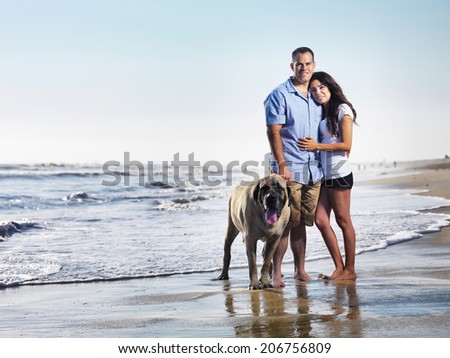 couple with pet dog posing on the beach.