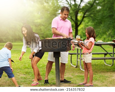 food getting served at family barbecue while children play